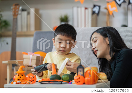 Halloween Crafts. A mother and son creating festive decorations together. 129727996