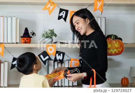 Halloween Celebration. A mother and child sharing joy while preparing festive decorations. Halloween Celebration. A mother and child sharing joy while preparing festive decorations. 129728027