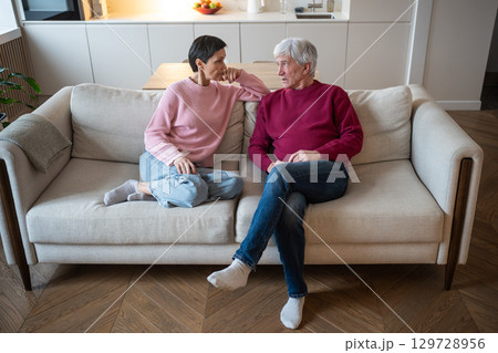 Elderly woman empathetically listen talking man on living room sofa at home. Senior couple bonding Elderly woman empathetically listen talking man on living room sofa at home. Senior couple bonding 129728956