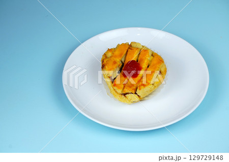 A delicious lattice-topped pie or tart with a cherry on top, served on a white plate with a light blue background. A delicious lattice-topped pie or tart with a cherry on top, served on a white plate with a light blue background. 129729148