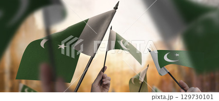 Pakistan flags in their hands on a blurred urban background 129730101