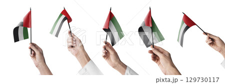 The Arab Emirates flag in hand in different angles on a white background The Arab Emirates flag in hand in different angles on a white background 129730117