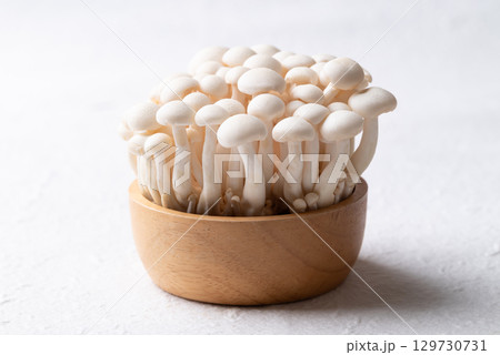 Fresh white Shimeji mushroom in wooden bowl on white background Fresh white Shimeji mushroom in wooden bowl on white background 129730731