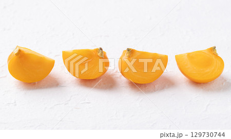 Sliced fresh ripe persimmon on white background, Autumn sweet fruit Sliced fresh ripe persimmon on white background, Autumn sweet fruit 129730744