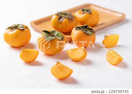 Sliced fresh ripe persimmon on white background, Autumn sweet fruit Sliced fresh ripe persimmon on white background, Autumn sweet fruit 129730745