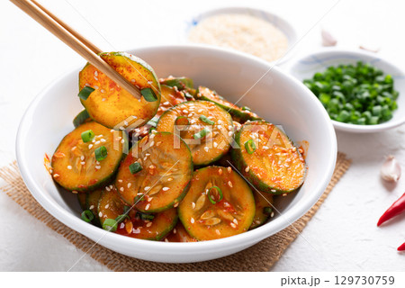Korean cucumber salad (Oi muchim) in bowl with chopsticks on white background, Korean side dish 129730759