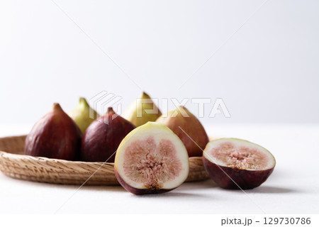 Fresh half fig and whole fruit in basket on white background, Autumn fruit Fresh half fig and whole fruit in basket on white background, Autumn fruit 129730786