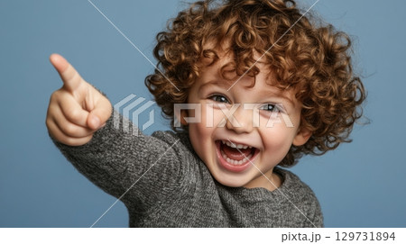 happy toddler boy pointing with curly hair 129731894