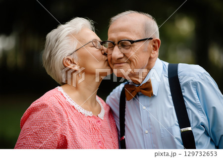 Elderly Couple Sharing a Tender Moment in a Serene Park Setting During a Sunny Afternoon 129732653