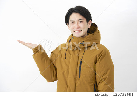ダウンジャケットを着た男性 左側を手のひらで指す 白背景 ダウンジャケットを着た男性 左側を手のひらで指す 白背景 129732691