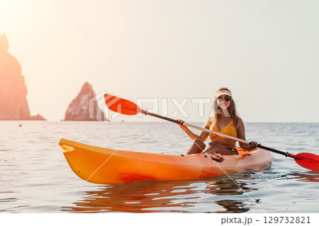 Kayaking, Woman, Sea - Young woman kayaking on calm ocean water with scenic cliffs in the background. 129732821