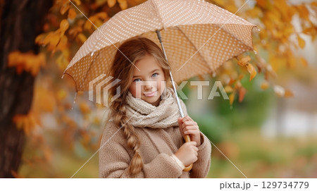 Young caucasian girl with umbrella in autumn park. 129734779