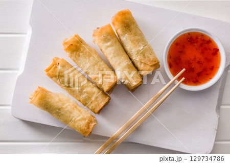 Fried spring rolls with sweet and saur sauce on white table. Top view. Fried spring rolls with sweet and saur sauce on white table. Top view. 129734786