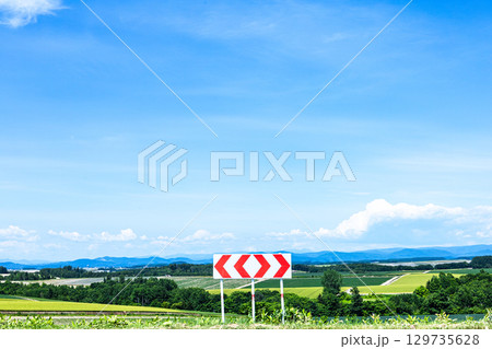 青空が広がる夏の北海道の風景と左右に分かれる分岐標識 129735628