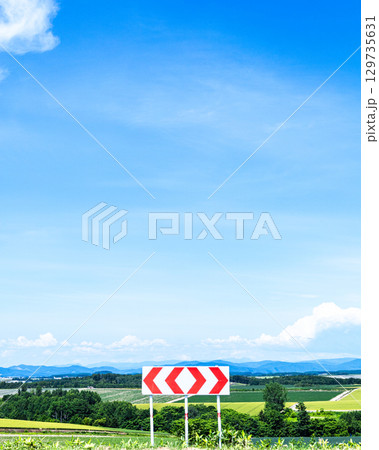 青空が広がる夏の北海道の風景と左右に分かれる分岐標識 129735631