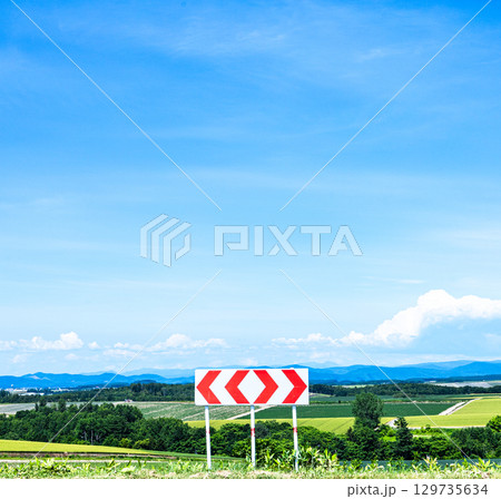 青空が広がる夏の北海道の風景と左右に分かれる分岐標識 青空が広がる夏の北海道の風景と左右に分かれる分岐標識 129735634