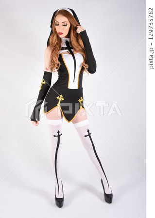 Tall, attractive, redhead model dressed as a fantasy Nun, isolated against a white background 129735782