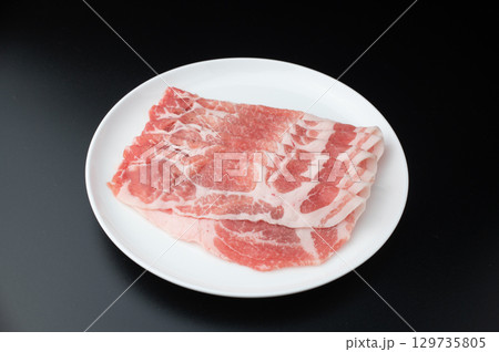 黒背景で白いお皿にのった豚ロース 薄切りスライスの生肉 黒背景で白いお皿にのった豚ロース 薄切りスライスの生肉 129735805