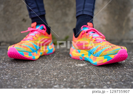 Man wearing colorful running shoes on pavement 129735907
