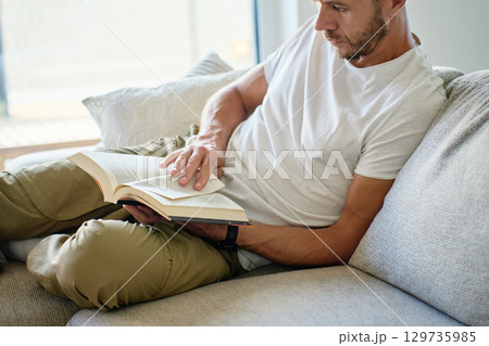 Man reading book on sofa at home Man reading book on sofa at home 129735985