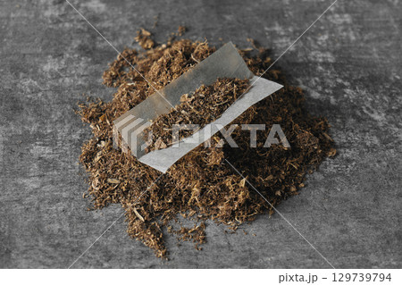 Tobacco leaves arranged for rolling cigarettes on a gray background 129739794