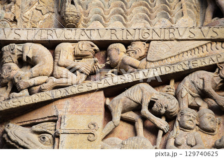 Stone carvings depicting Hell on entrance of Abbey Church of Sainte-Foy in Conques, France 129740625