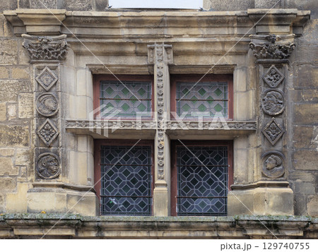 Historic window in Sarlat-la-Caneda, France, showcasing intricate stone carvings and stained glass Historic window in Sarlat-la-Caneda, France, showcasing intricate stone carvings and stained glass 129740755