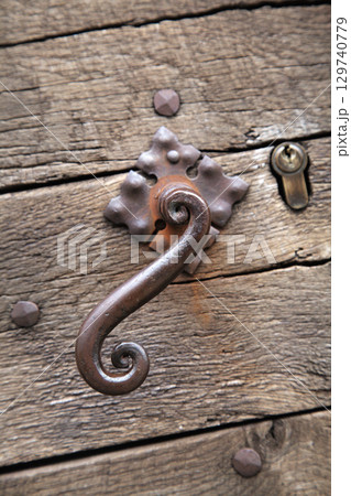 Decorative metal latch on weathered wooden door in France Decorative metal latch on weathered wooden door in France 129740779