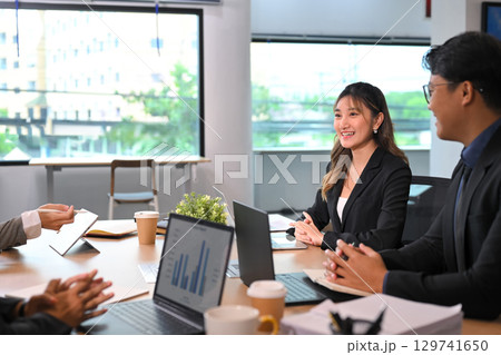 Business team meeting in modern office, colleagues discussing strategy with laptops and charts Business team meeting in modern office, colleagues discussing strategy with laptops and charts 129741650