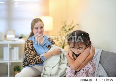 Upset little girl crossing her arms and pouting, refusing to go to school Upset little girl crossing her arms and pouting, refusing to go to school 129741659