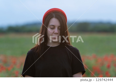 Young Woman in Poppy Field with Red Hat 129742444