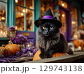 ハロウィンカボチャの上に乗った魔女帽の黒猫 129743138