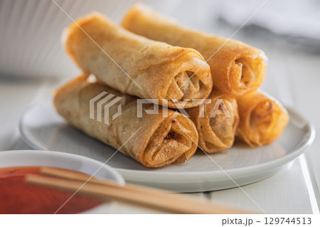 Fried spring rolls on plate on white table. Fried spring rolls on plate on white table. 129744513