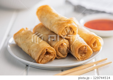 Fried spring rolls on plate on white table. Fried spring rolls on plate on white table. 129744514