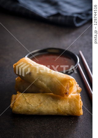 Fried spring rolls and sweet and sour sauce on wooden table. Fried spring rolls and sweet and sour sauce on wooden table. 129744516
