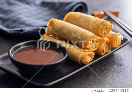 Fried spring rolls and sweet and sour sauce on wooden table. Fried spring rolls and sweet and sour sauce on wooden table. 129744517