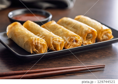 Fried spring rolls and sweet and sour sauce on wooden table. Fried spring rolls and sweet and sour sauce on wooden table. 129744521