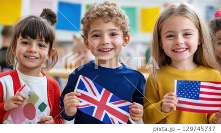 Children holding US and UK flag learning English language in classroom. 129745737