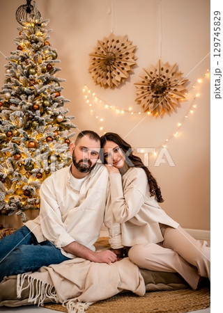 Cozy Holiday Couple Relaxing by Christmas Tree 129745829