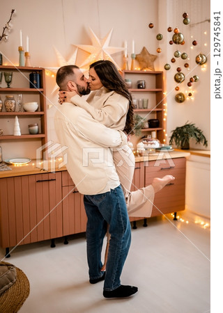 Romantic Couple Sharing a Kiss in Festive Kitchen 129745841