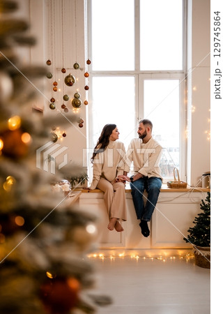 Cozy couple enjoying christmas atmosphere by the window 129745864