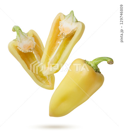 Yellow pepper and two halves flying on a white background. Isolated 129746809