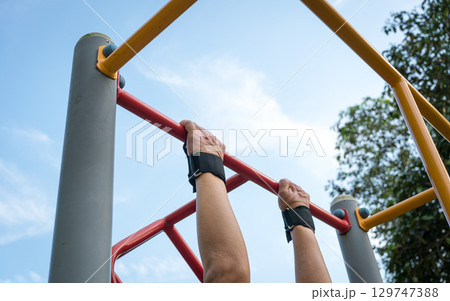 Man doing pull ups workout on the steel bar in the park. Man doing pull ups workout on the steel bar in the park. 129747388