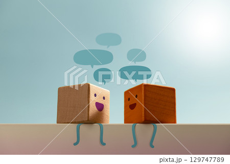 Smiling wooden blocks engage in conversation with speech bubbles. reflects friendly communication or therapeutic talk therapy for mental healing 129747789