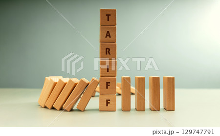 Falling dominoes halted by a vertical stack labeled TARIFF, Trade barriers affect global economies in domino impact Falling dominoes halted by a vertical stack labeled TARIFF, Trade barriers affect global economies in domino impact 129747791