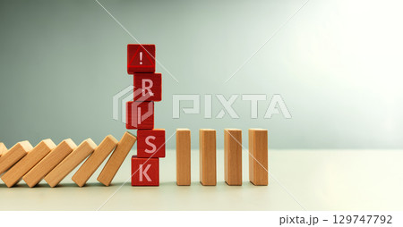 Row of falling dominos halted by red blocks spelling RISK. risk management, crisis prevention, and financial protection 129747792