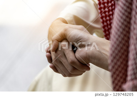 Arab Businessman shaking hands together. Teamwork business partner wear Muslim dress Shake Hands with Partnership Concept. Success UAE diversity people trust make commitment by handshake 129748205