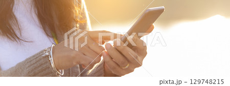 Banner Woman hands holding mobile phone outdoor surfing internet online technology lifestyle. Close up woman hand using smartphone gadget text message panoramic with copy space. Technology lifestyle 129748215