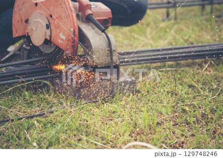 Construction Worker hands using Welding machinery iron metal sparking. Men hands wear protective glove Hot flame metal work cutting fire iron workshop. Locksmith use Welding machine cut metal process 129748246