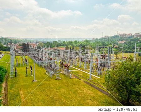 High-voltage power substation in a green landscape. Energy infrastructure, electricity distribution, and technology integration in modern urban planning. 129748363